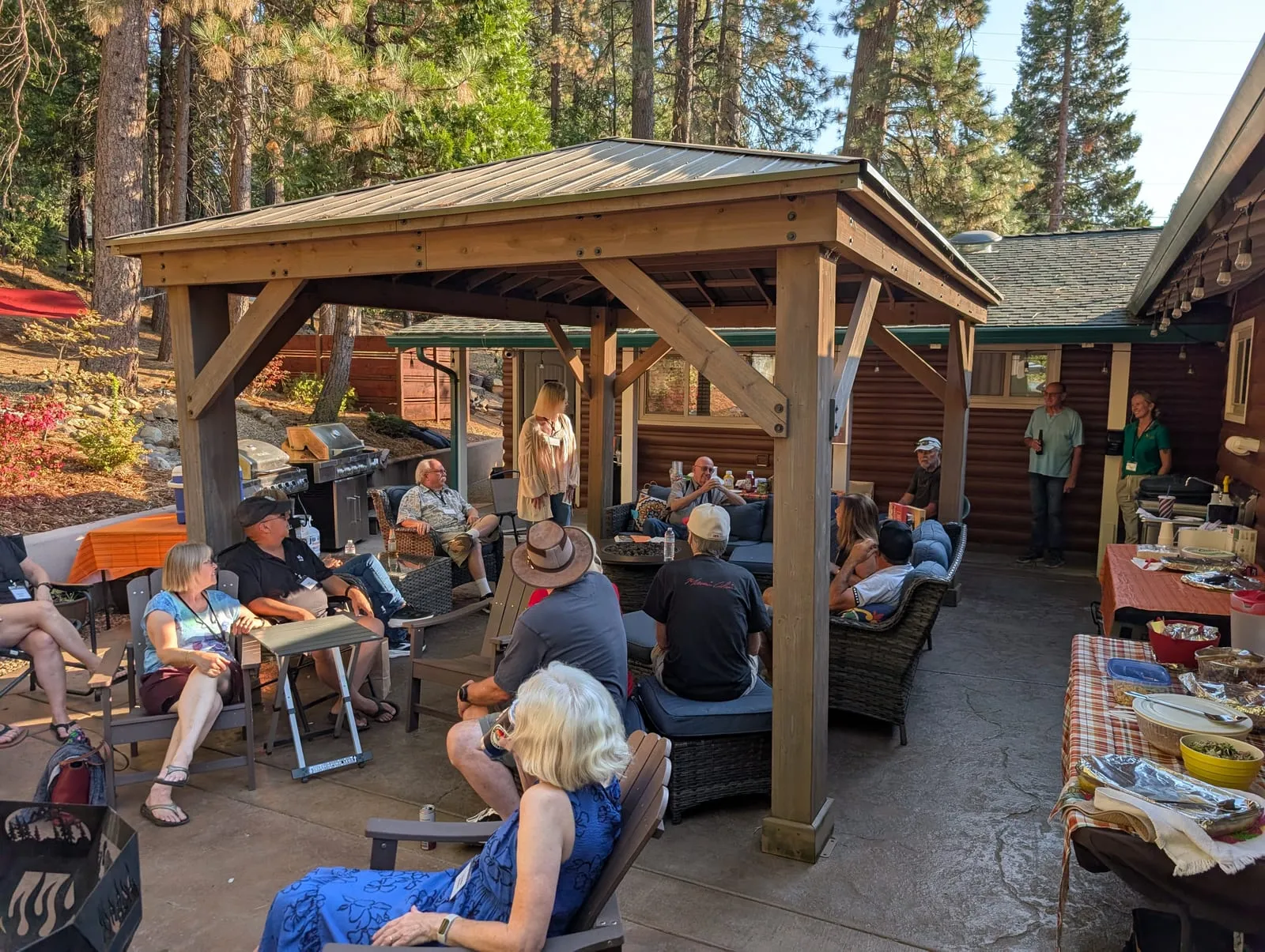 ERSN members gathered around the fire pit on the covered patio at Meadowmont Lodge, surrounded by tall pines